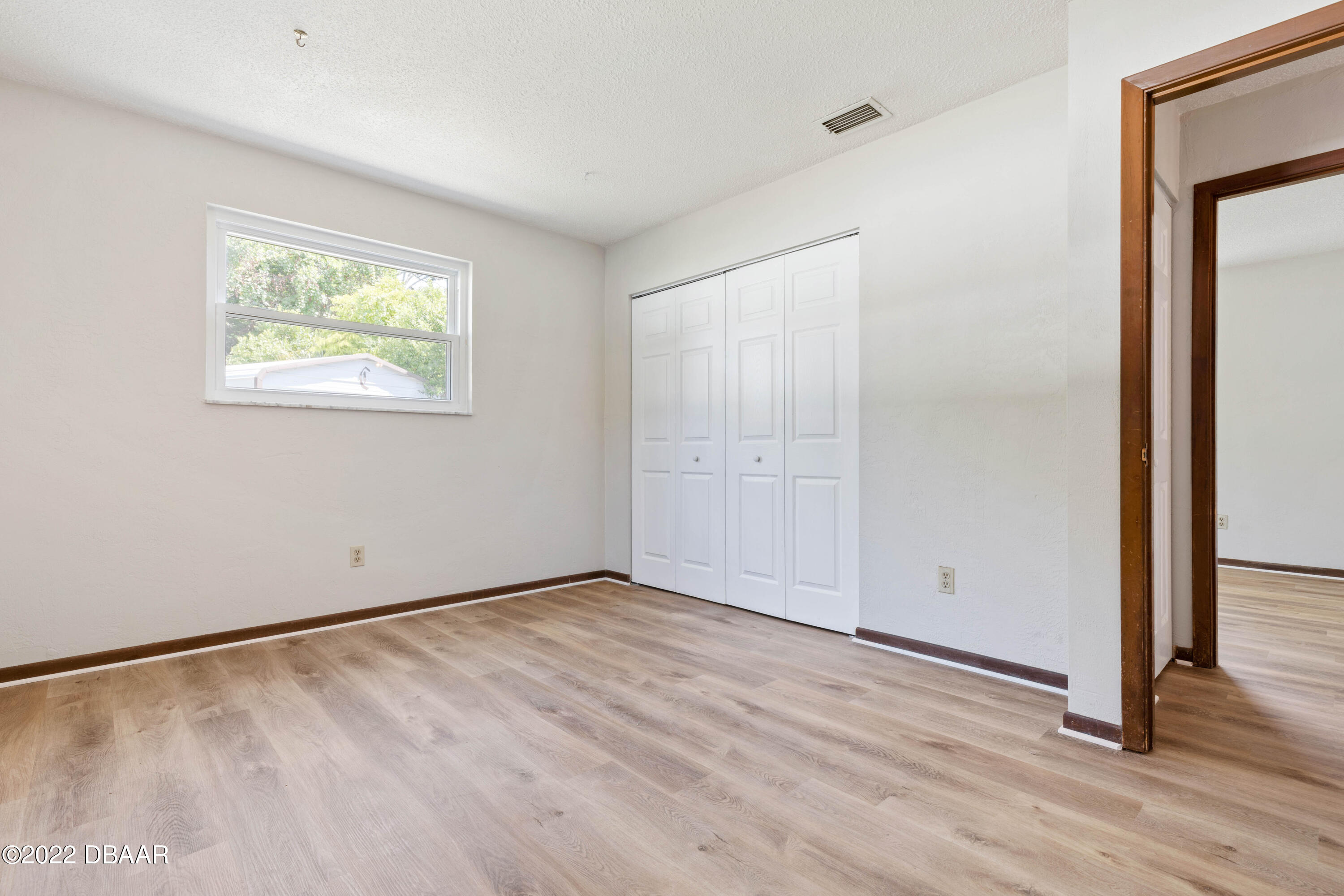 64 Cumberland Avenue Ormond Beach, FL 32174 - Photo 17 of 38 a view of an empty room with wooden floor and a window