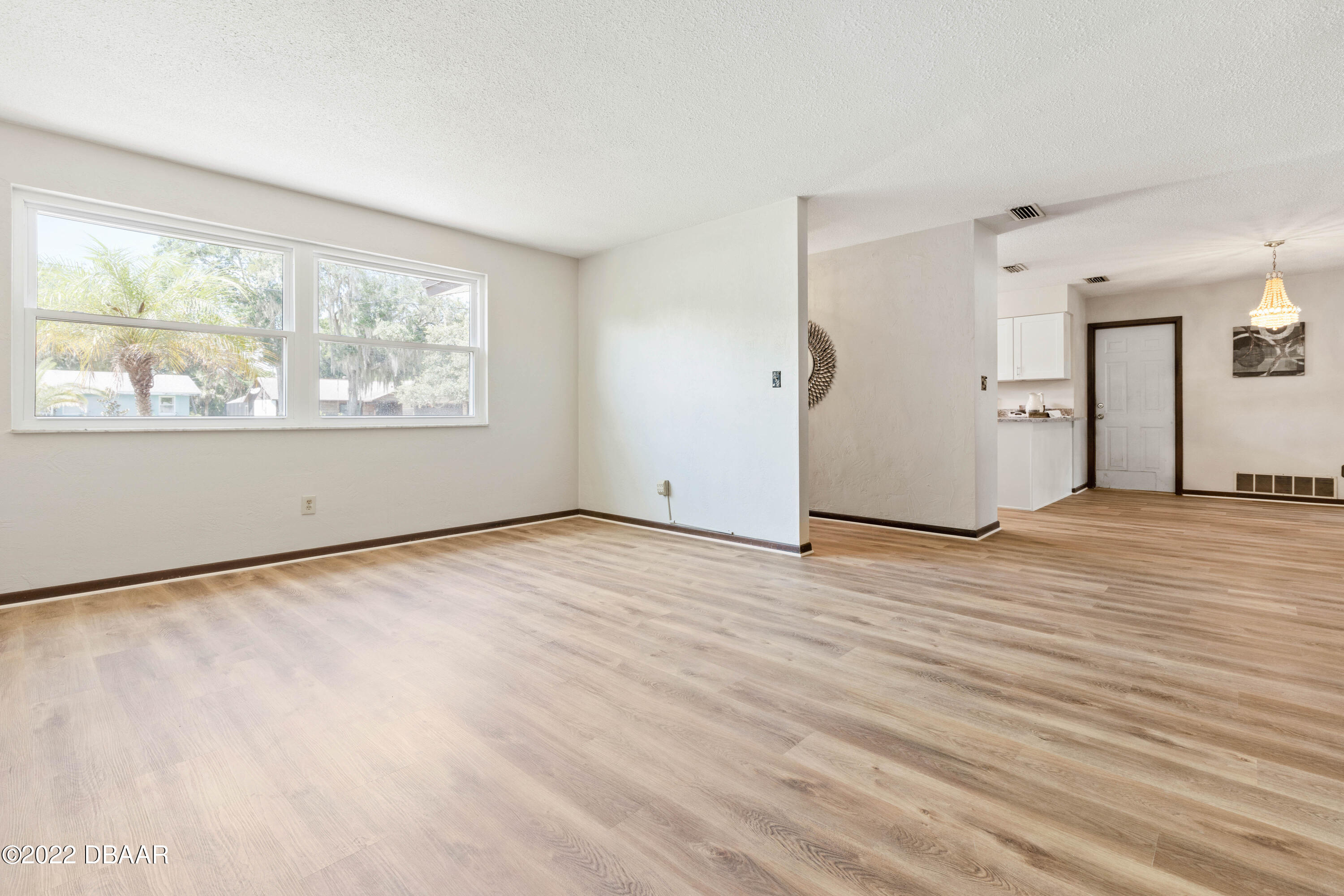 64 Cumberland Avenue Ormond Beach, FL 32174 - Photo 5 of 38 an empty room with wooden floor and windows