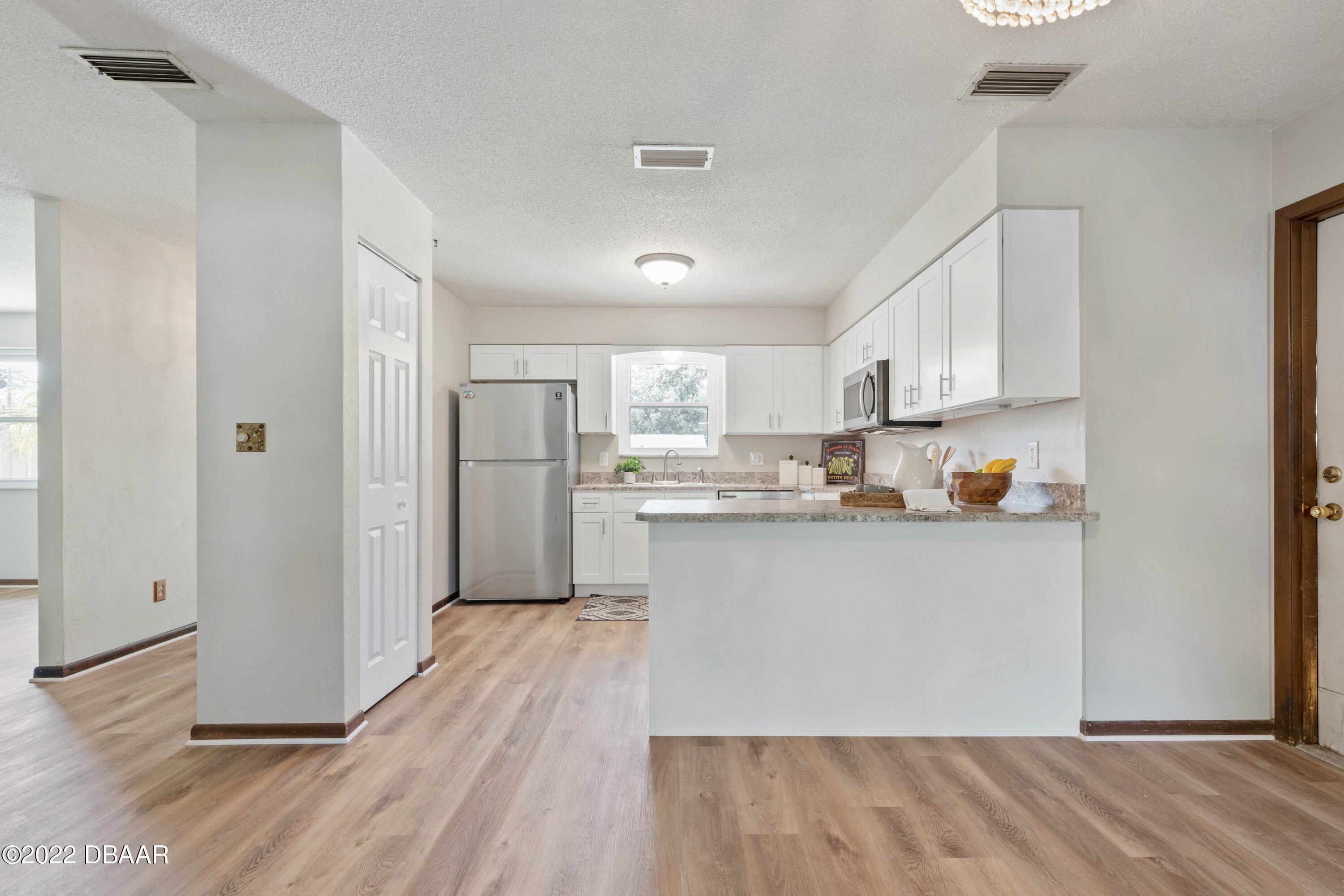 64 Cumberland Avenue Ormond Beach, FL 32174 - Photo 9 of 38 a kitchen with stainless steel appliances granite countertop a refrigerator a sink and white cabinets with wooden floor