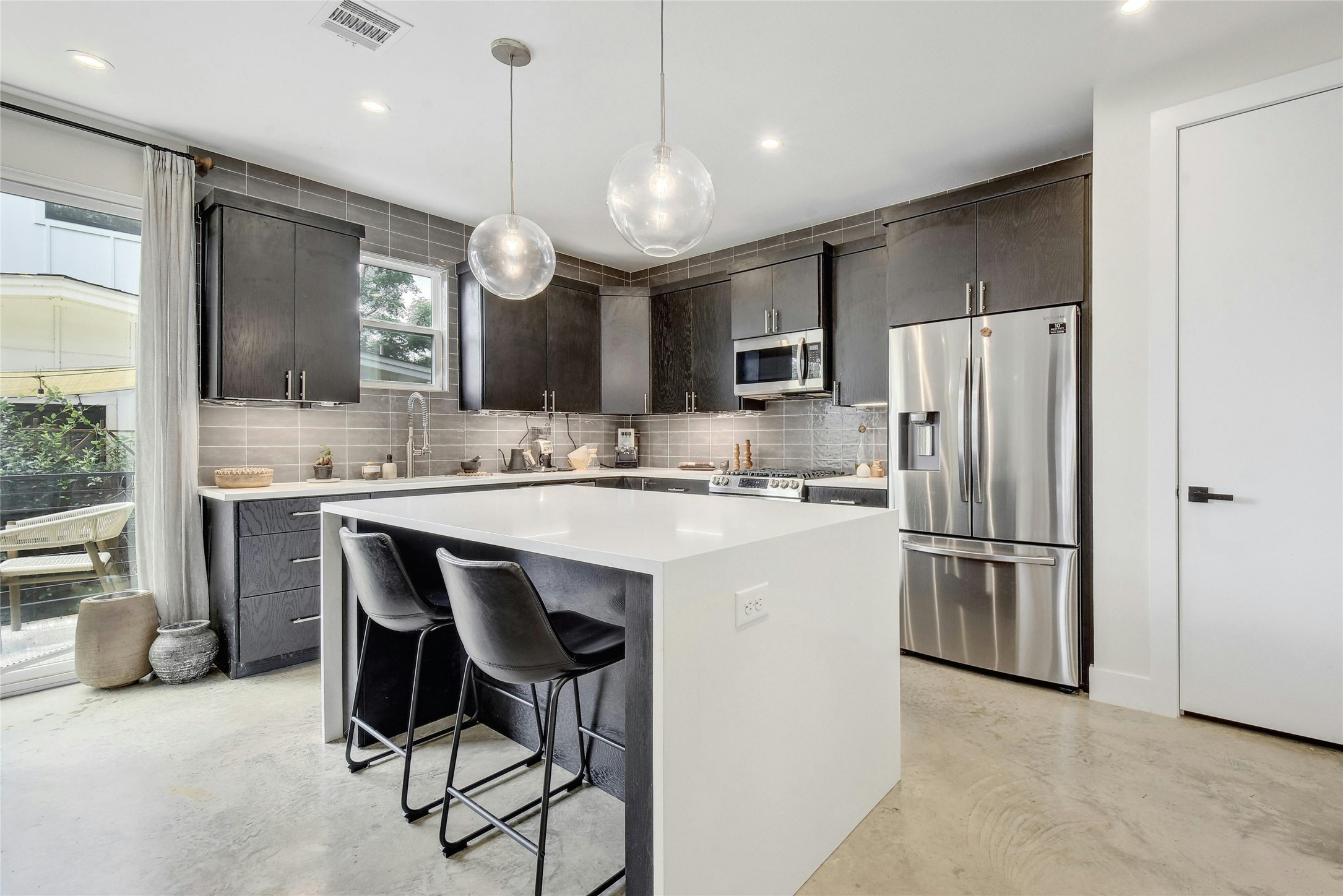 4606 Ledesma Road, Unit 2 Austin, TX 78721 - Photo 9 of 33 A contemporary kitchen features an island with seating, sleek cabinetry, and stainless steel appliances.