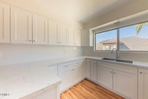 a kitchen with white cabinets and sink