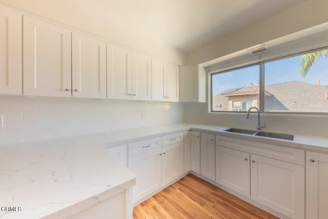 a kitchen with white cabinets and sink
