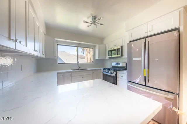 a kitchen with stainless steel appliances a refrigerator and a stove top oven