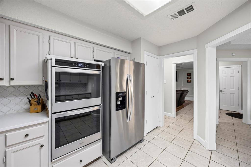 112 Saddle Hills Road Burleson, TX 76028 - Photo 18 of 38 a kitchen with white cabinets and refrigerator