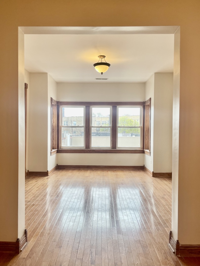Undisclosed Address Chicago, IL 60618 - Photo 2 of 14 a view of an empty room with wooden floor and a window
