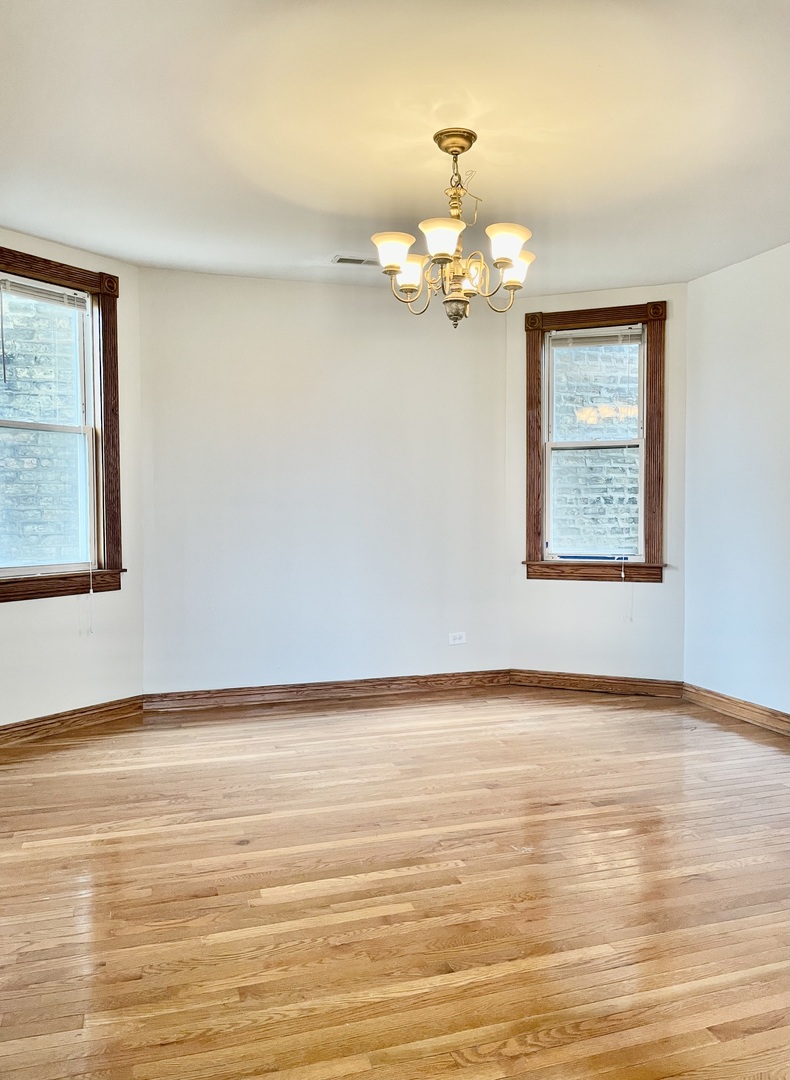 Undisclosed Address Chicago, IL 60618 - Photo 6 of 14 a view of an empty room with chandelier fan and wooden floor