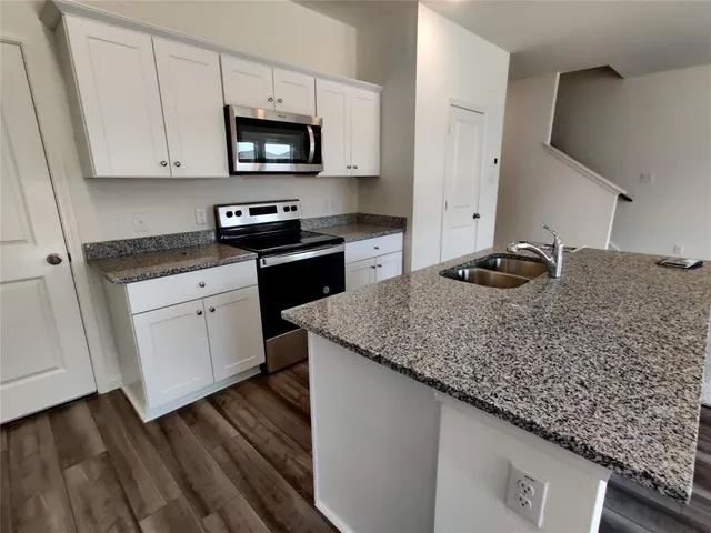 a kitchen with stainless steel appliances granite countertop a sink a stove and microwave