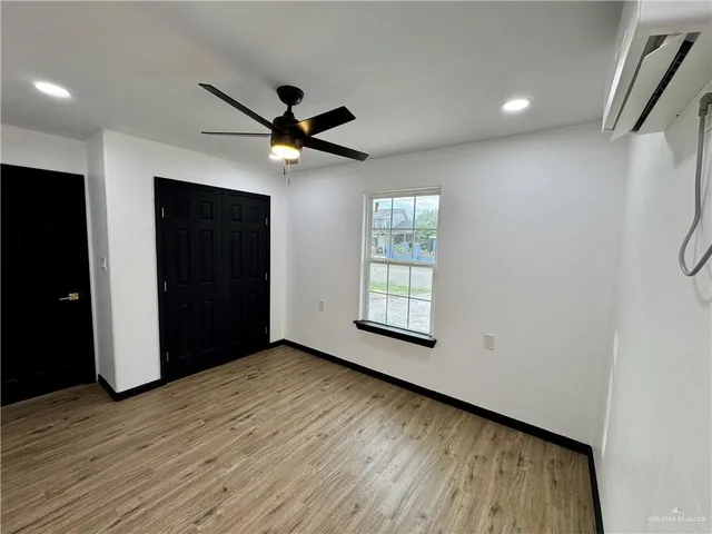 a view of an empty room with a window and a kitchen
