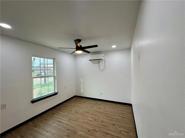 an empty room with wooden floor ceiling fan and windows