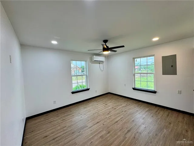 a view of an empty room with wooden floor and a window