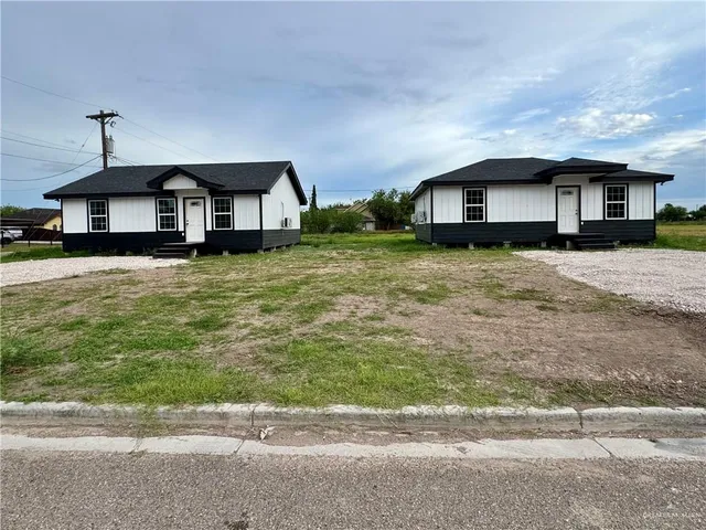 a view of a house with a big yard plants and large trees