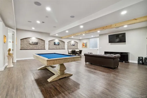 a living room with furniture pool table and a wooden floor