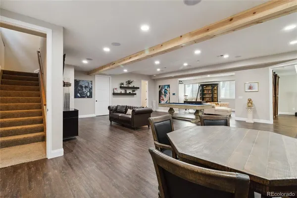 a living room with couches kitchen view and a refrigerator