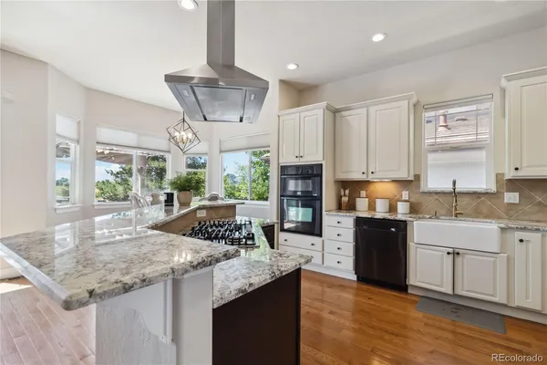 a kitchen with granite countertop kitchen island stainless steel appliances a sink stove and cabinets