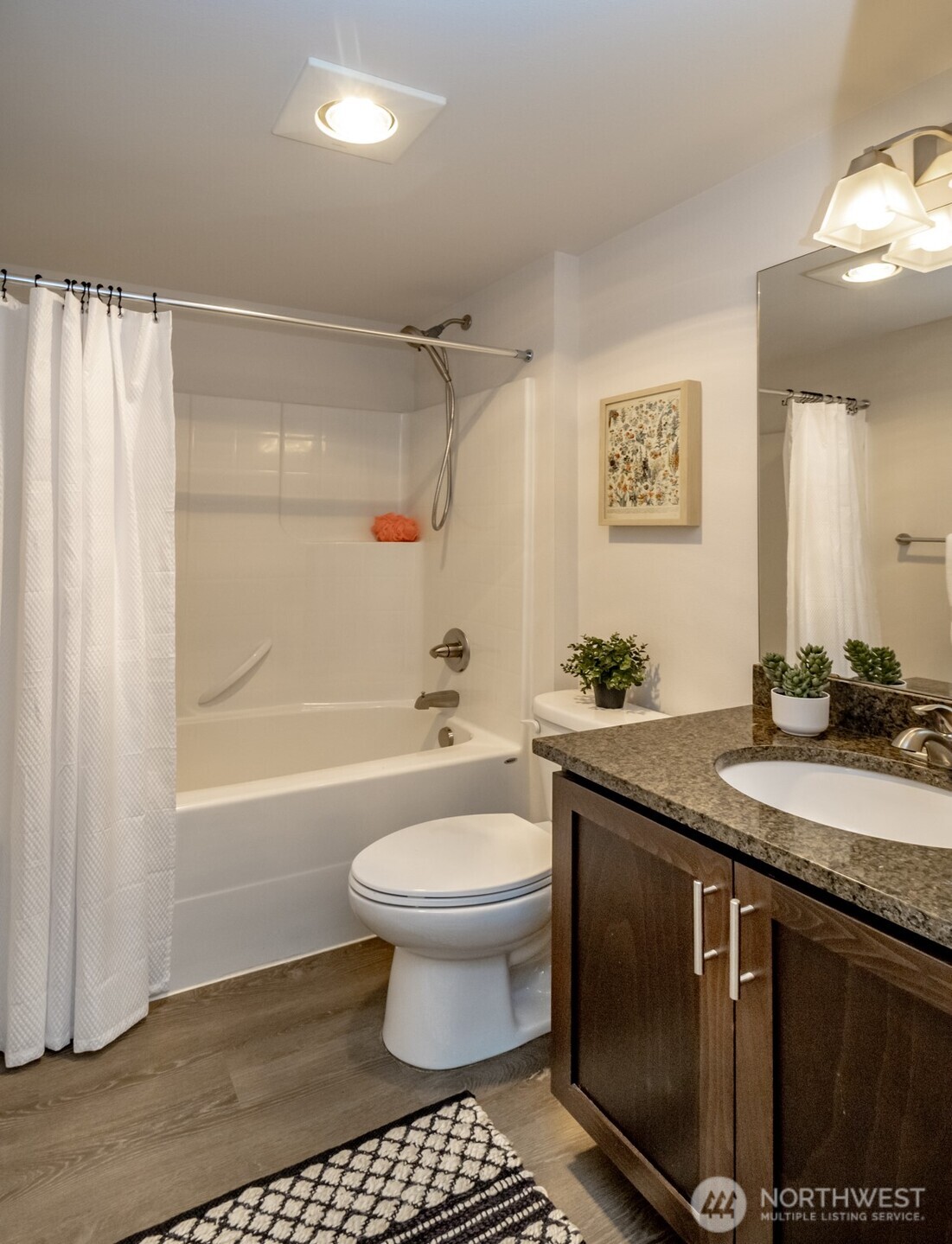 6830 31st Avenue Southwest Seattle, WA 98126 - Photo 26 of 28 a bathroom with a granite countertop sink toilet a mirror a bathtub and shower