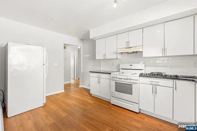 a kitchen with granite countertop white cabinets and white appliances