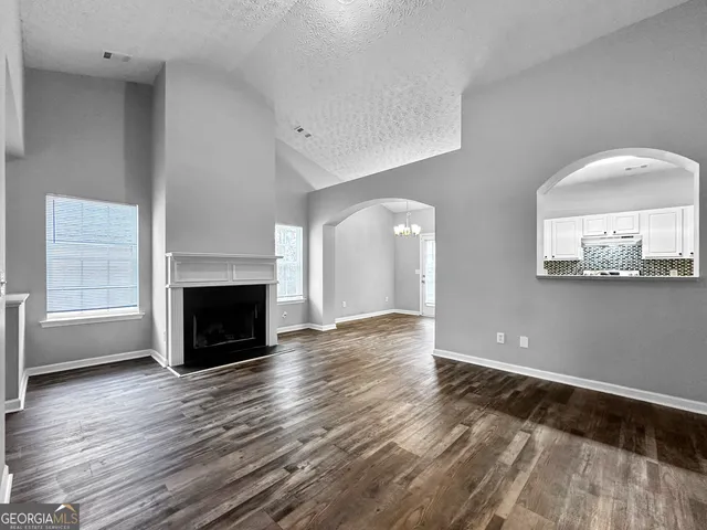 an empty room with wooden floor a fireplace and windows