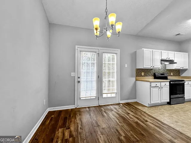 a view of a kitchen with a stove wooden cabinet wooden floor and chandelier