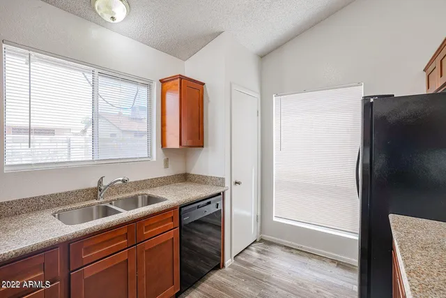 a kitchen with stainless steel appliances granite countertop a sink a refrigerator a window and a counter space