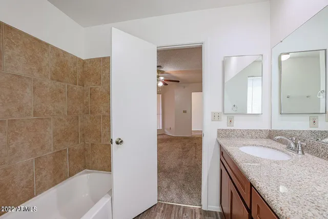 a bathroom with a granite countertop sink a mirror and a bathtub