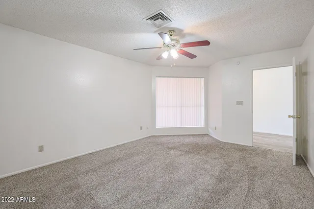 an empty room with a chandelier fan and windows