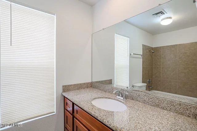a bathroom with a granite countertop sink and a mirror
