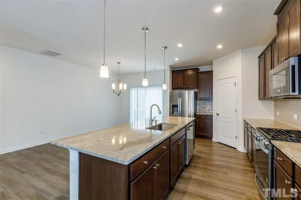 a kitchen with granite countertop kitchen island stainless steel appliances a sink stove and refrigerator