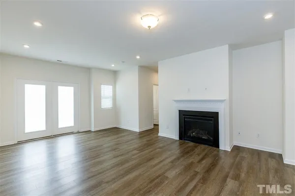 an empty room with wooden floor fireplace and windows