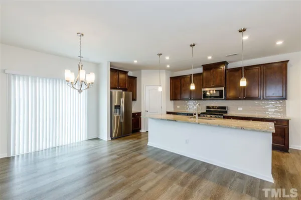 a large kitchen with granite countertop a large counter top a sink stainless steel appliances and cabinets