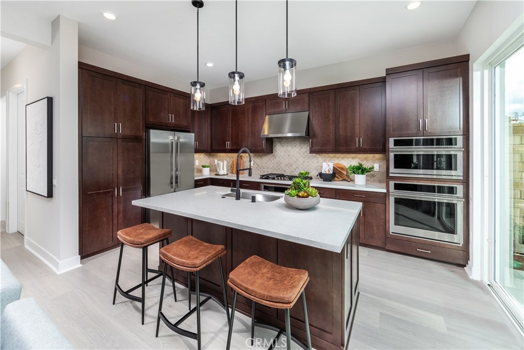 224 Lily Loop Irvine, CA 92618 - Photo 4 of 13 a kitchen with stainless steel appliances granite countertop a sink a stove a refrigerator cabinets and chairs