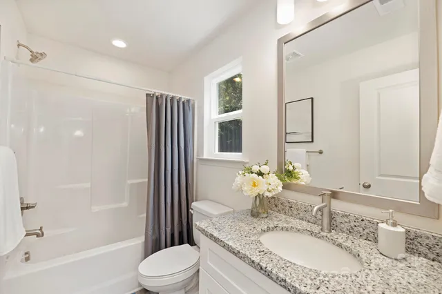 a bathroom with a granite countertop sink toilet and shower
