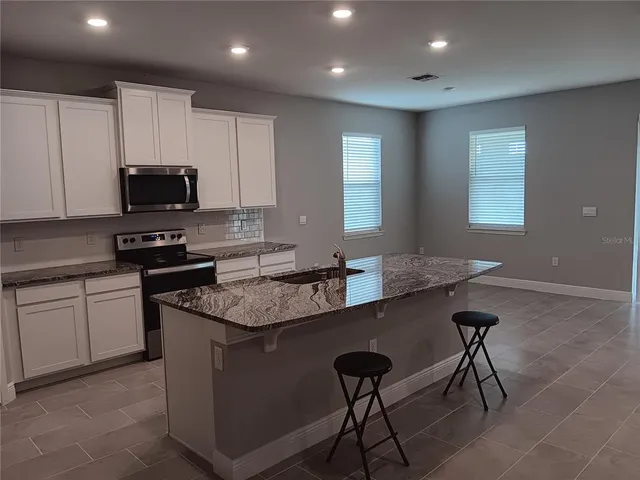 a kitchen with granite countertop a stove sink and cabinets