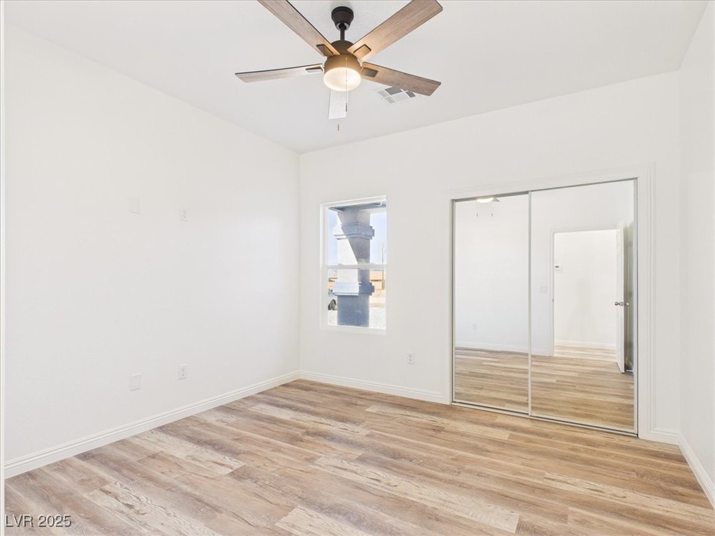 931 Lone Pine Road Pahrump, NV 89048 - Photo 10 of 48 Unfurnished bedroom featuring light wood-type flooring, a ceiling fan, and a closet