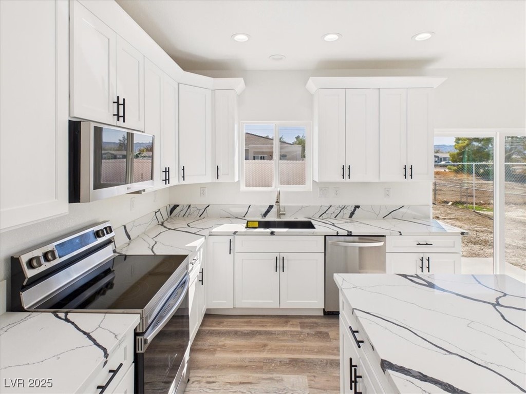 931 Lone Pine Road Pahrump, NV 89048 - Photo 6 of 48 Kitchen featuring stainless steel appliances, light stone countertops, light wood-type flooring, white cabinetry, and recessed lighting