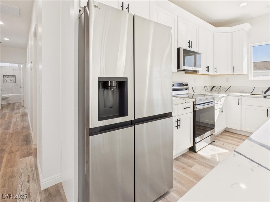931 Lone Pine Road Pahrump, NV 89048 - Photo 7 of 48 Kitchen featuring recessed lighting, appliances with stainless steel finishes, light wood-style floors, white cabinets, and light stone countertops
