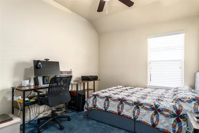 a bedroom with a bed a computer on a desk and chair
