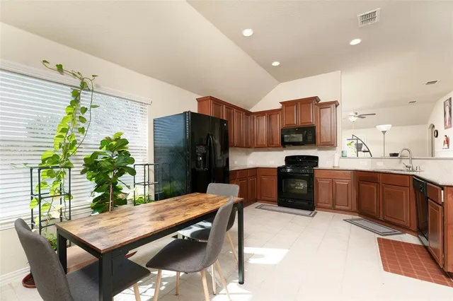 a kitchen with stainless steel appliances kitchen island granite countertop a refrigerator a stove a sink a dining table and chairs