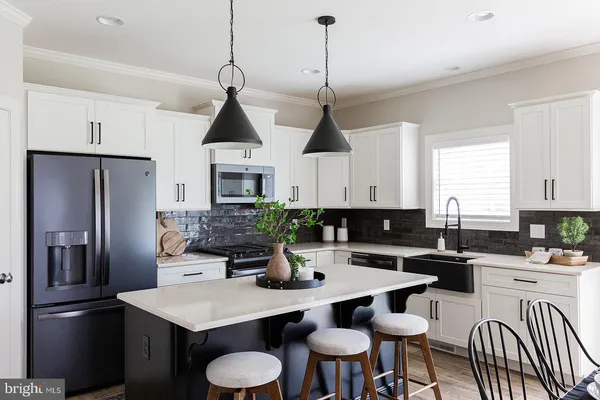 a kitchen with stainless steel appliances a dining table chairs stove refrigerator and cabinets