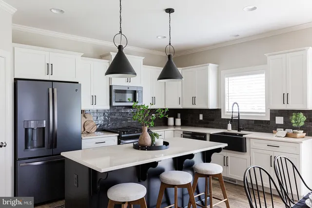 a kitchen with stainless steel appliances a dining table chairs stove refrigerator and cabinets