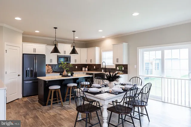 a open dining room with stainless steel appliances kitchen island granite countertop a dining table chairs and a refrigerator