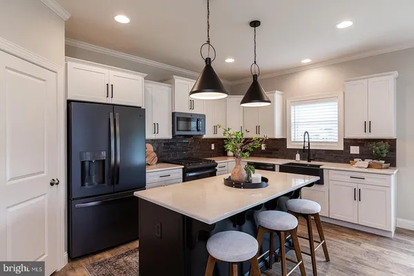 a kitchen with a refrigerator a sink a stove a dining table and chairs