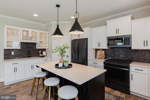 a kitchen with stainless steel appliances a sink a stove a refrigerator a dining table and chairs