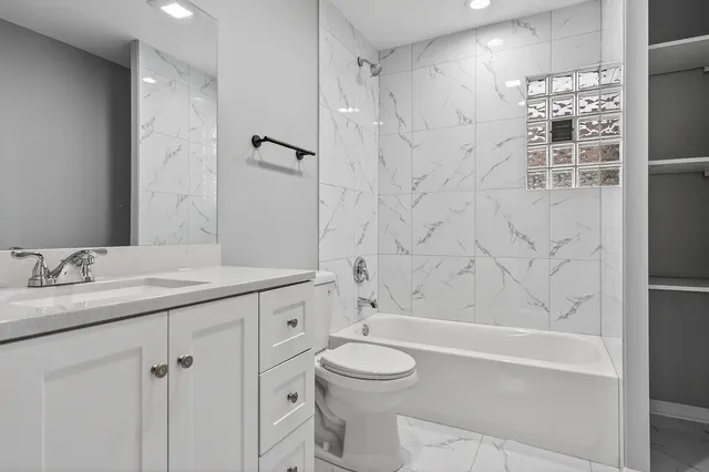 a bathroom with a granite countertop sink a toilet and shower