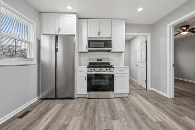 a kitchen with a refrigerator stove and wooden floors
