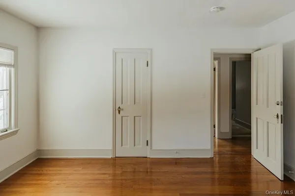 a view of an empty room with wooden floor and window