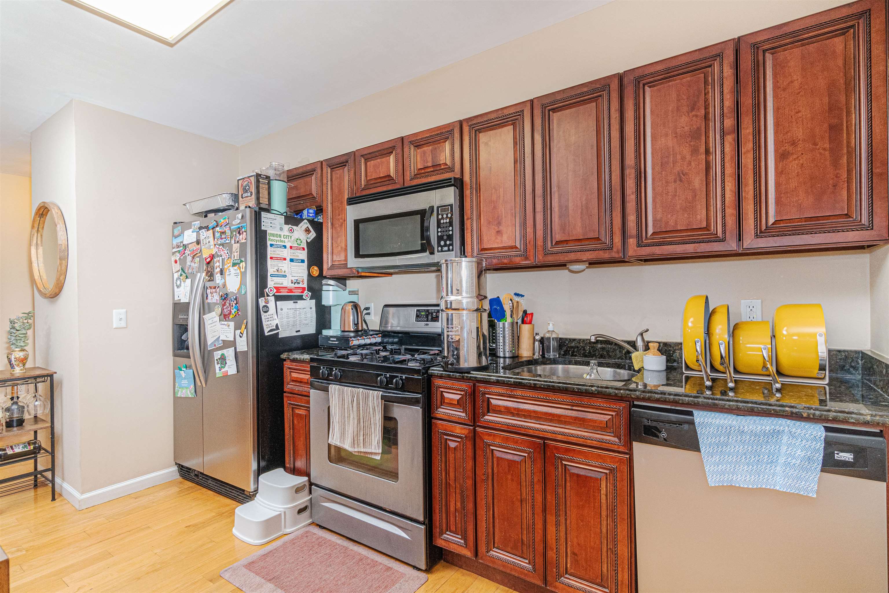 135 38th Street, Unit 302 Union City, NJ 07087 - Photo 11 of 18 a kitchen with stainless steel appliances granite countertop a stove top oven a sink dishwasher and cabinets with wooden floor