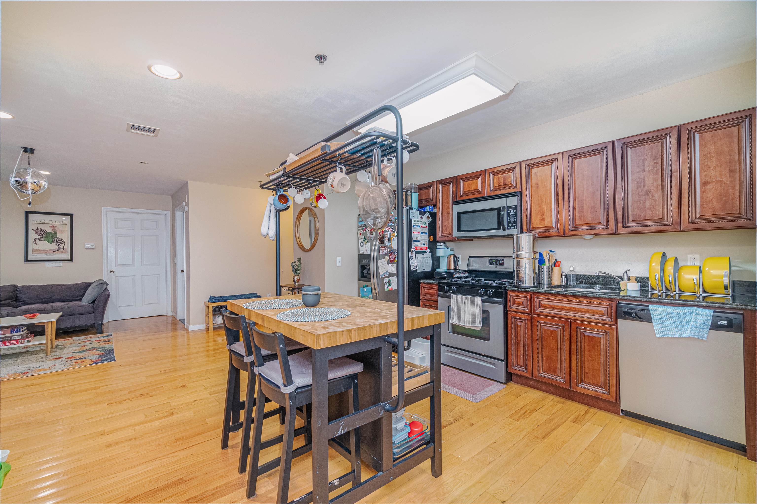 135 38th Street, Unit 302 Union City, NJ 07087 - Photo 8 of 18 a kitchen with stainless steel appliances granite countertop a stove top oven a sink a dining table and chairs with wooden floor