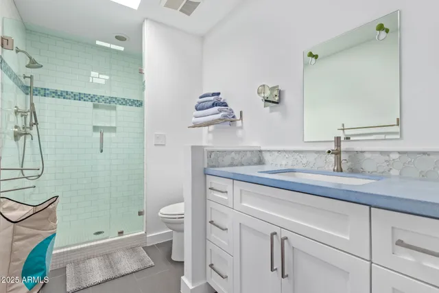 a bathroom with a granite countertop sink a toilet a shower and a mirror
