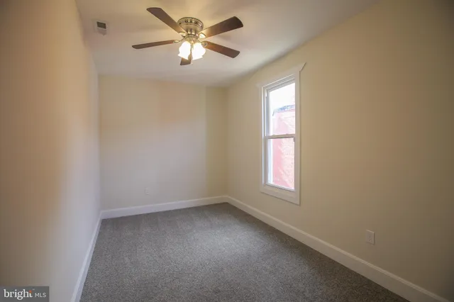 an empty room with windows and fan