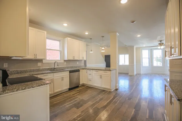 a large kitchen with granite countertop a large counter top space a sink stainless steel appliances and cabinets